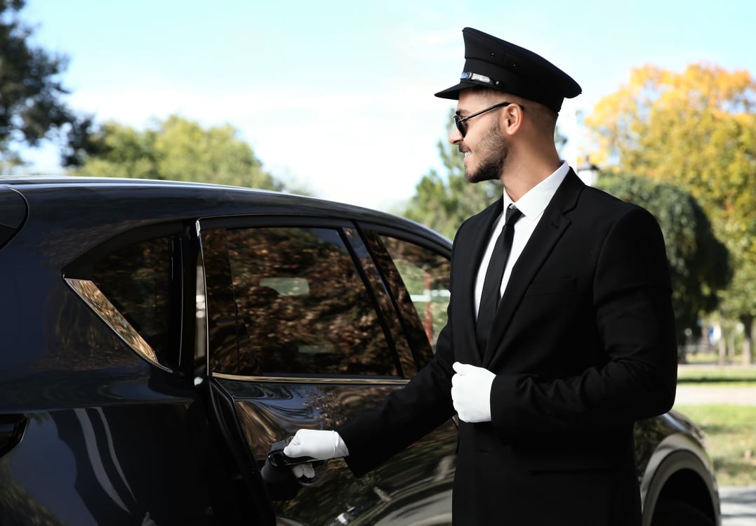 Young Handsome Driver Opening Luxury Car Door. Chauffeur Service